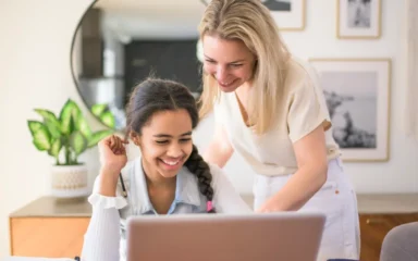 mom and girl smiling and looking the computer