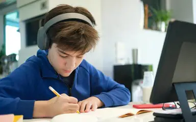 Kid studying wearing headphones.